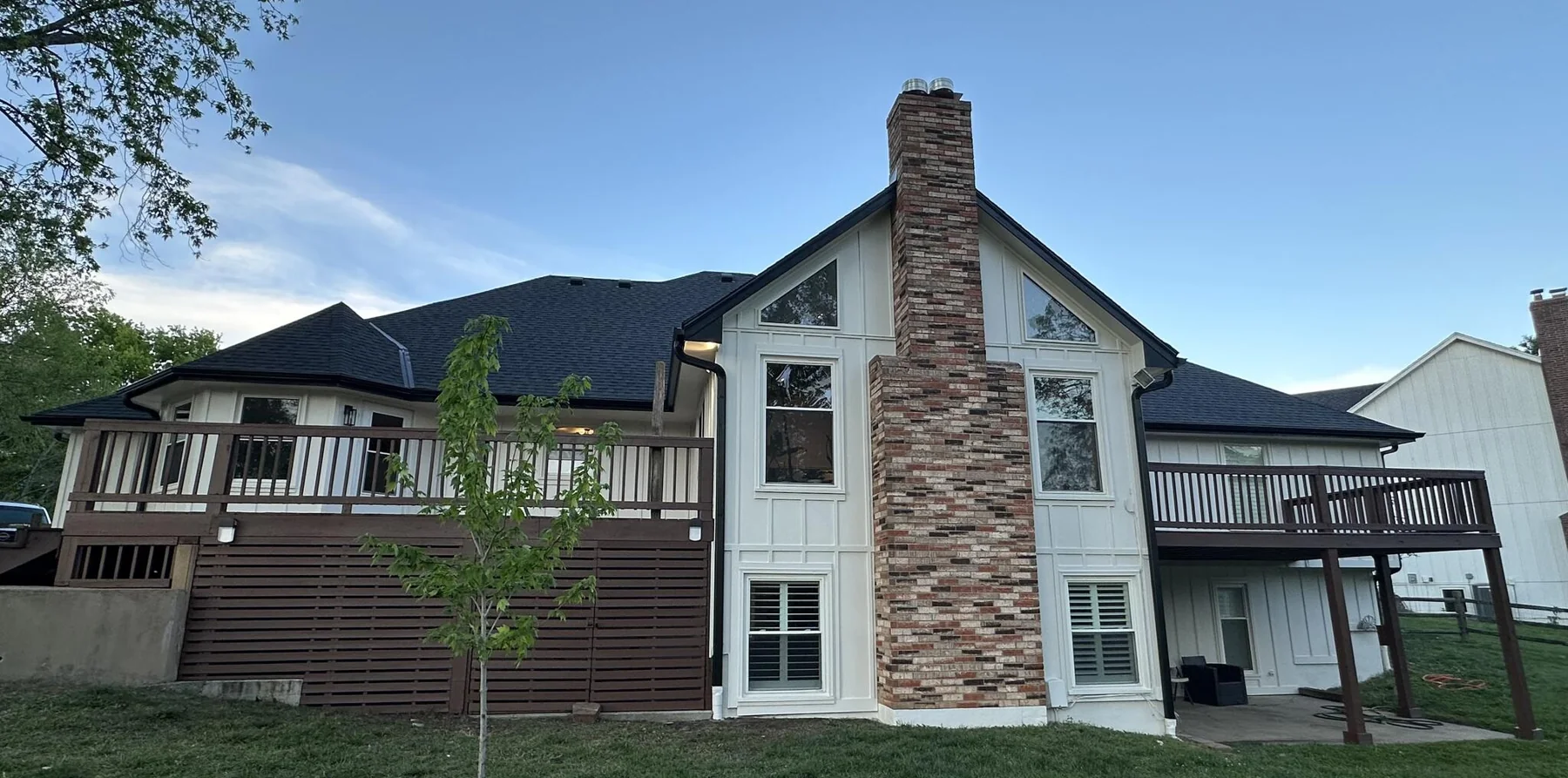 Wide rear view of a cream-sided home and deck